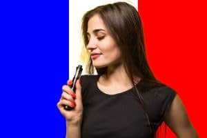 Jeune femme qui fume une cigarette électronique devant un drapeau de la France