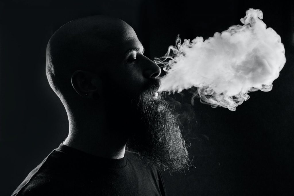 homme qui exhale de la vapeur de cigarette électronique